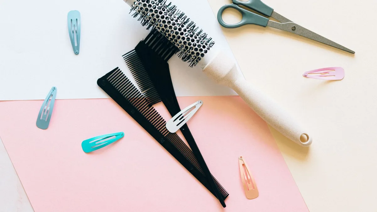 A flat lay of hairdressing tools on a pastel background, showcasing combs, brushes, and clips.
