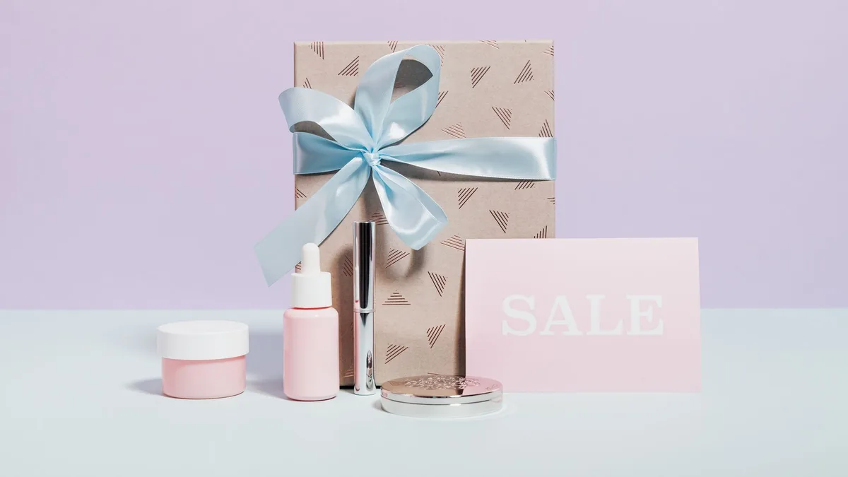 Stylish flat lay of beauty products and a gift with sale signage, perfect for promotions.
